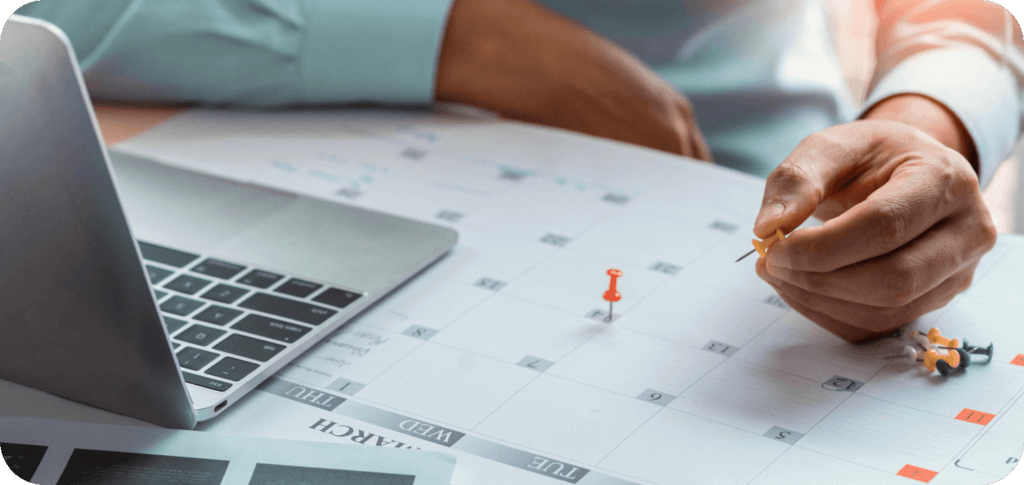 An office worker marking a calendar with pins